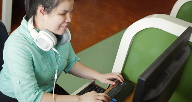Jeune femme aveugle utilisant un ordinateur avec un afficheur braille dynamique