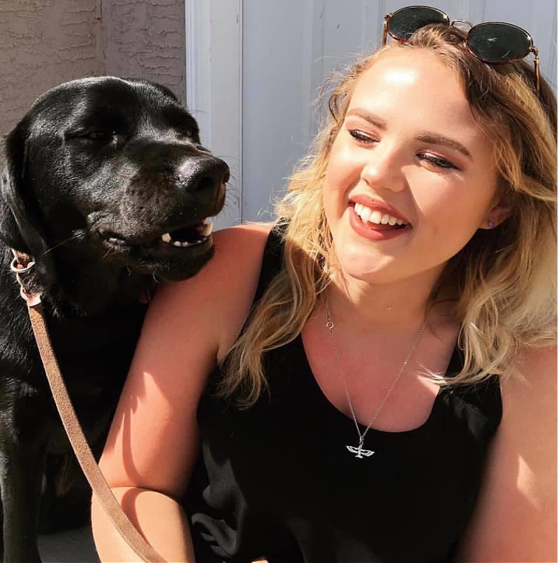A woman sits with her guide dog beside her.