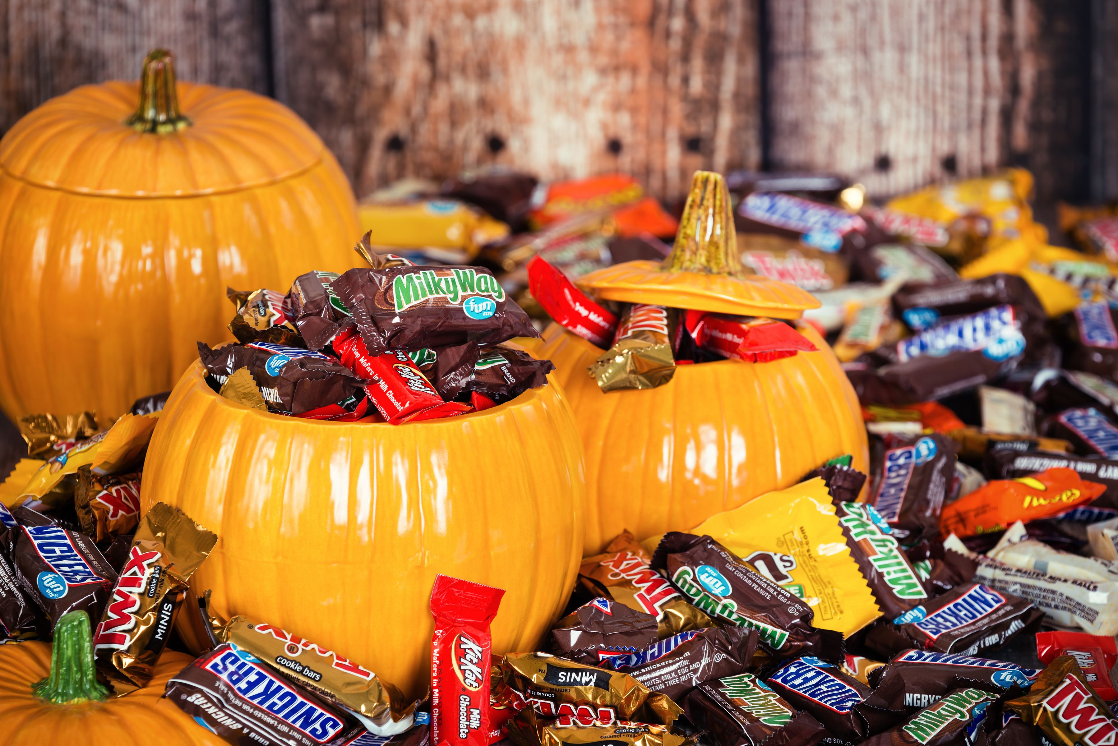 A variety of Halloween candy on a table with pumpkins