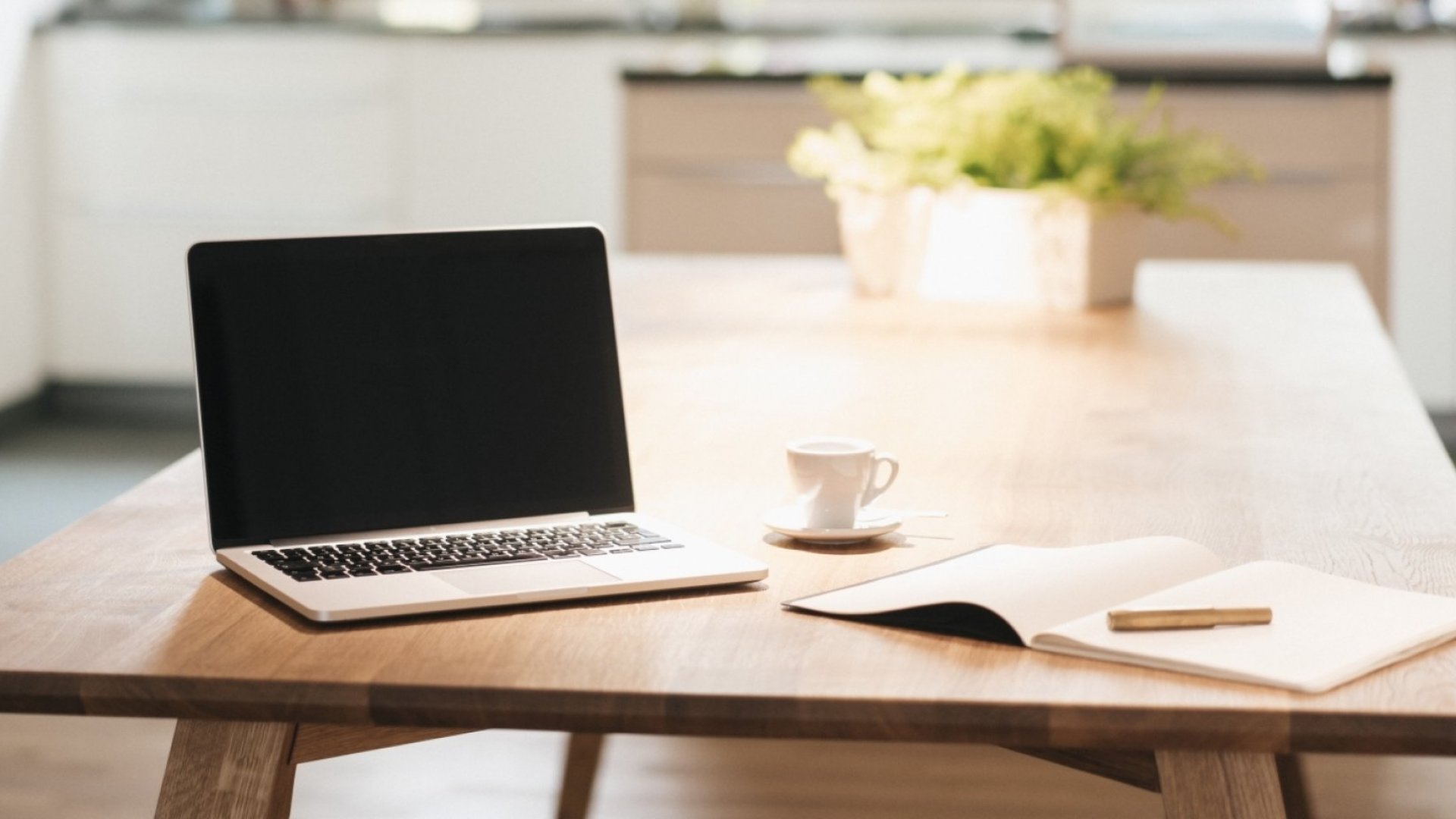 A laptop on a table with office supplies around