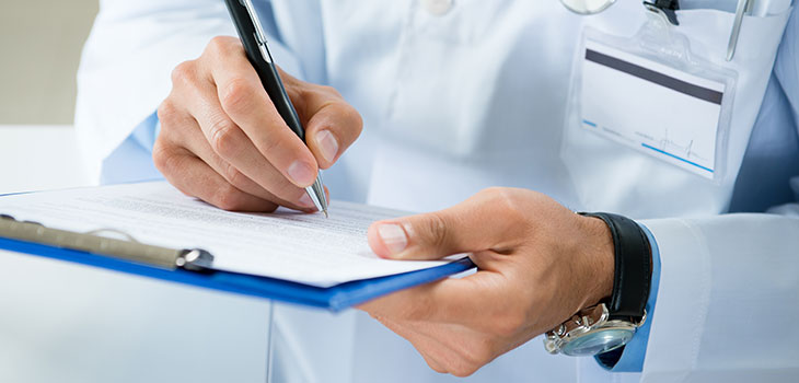A closeup of a doctor's hands writing on a medical chart. 