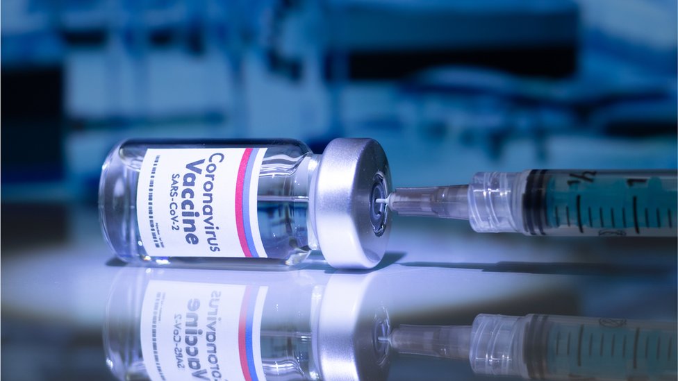 A needle in a vial that's labeled COVID-19 vaccine