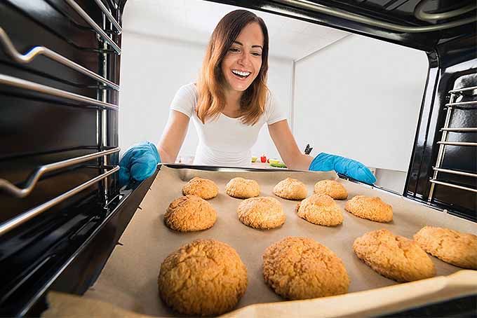 A women pulling cookies out of the oven