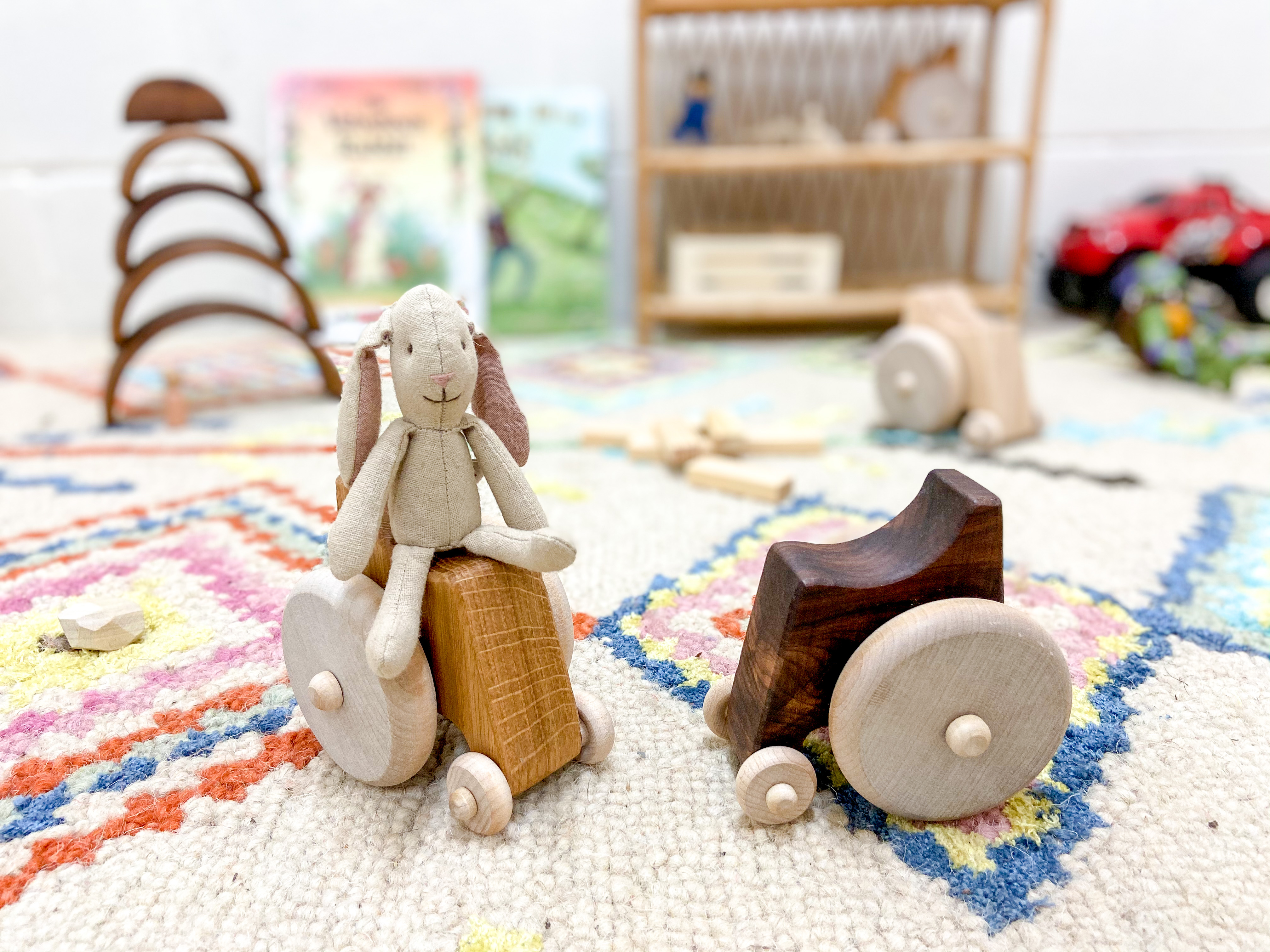 Two wooden toys with wheels and a bunny on one of them.