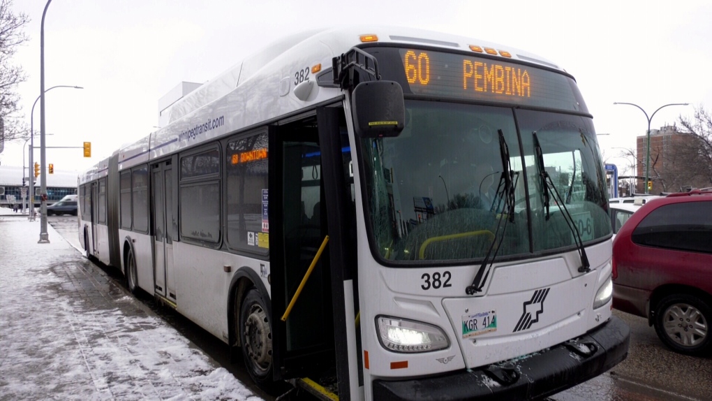 A Winnipeg Transit bus at a stop with a sidewalk covered in snow.