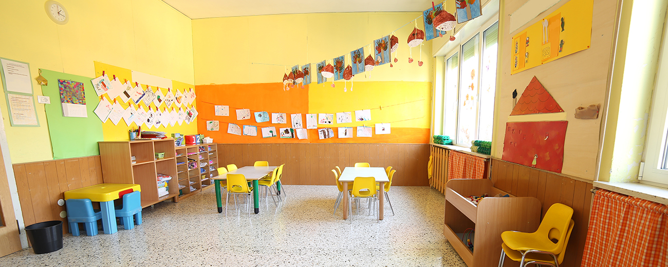 An empty childcare room with tables and chairs and decor. 