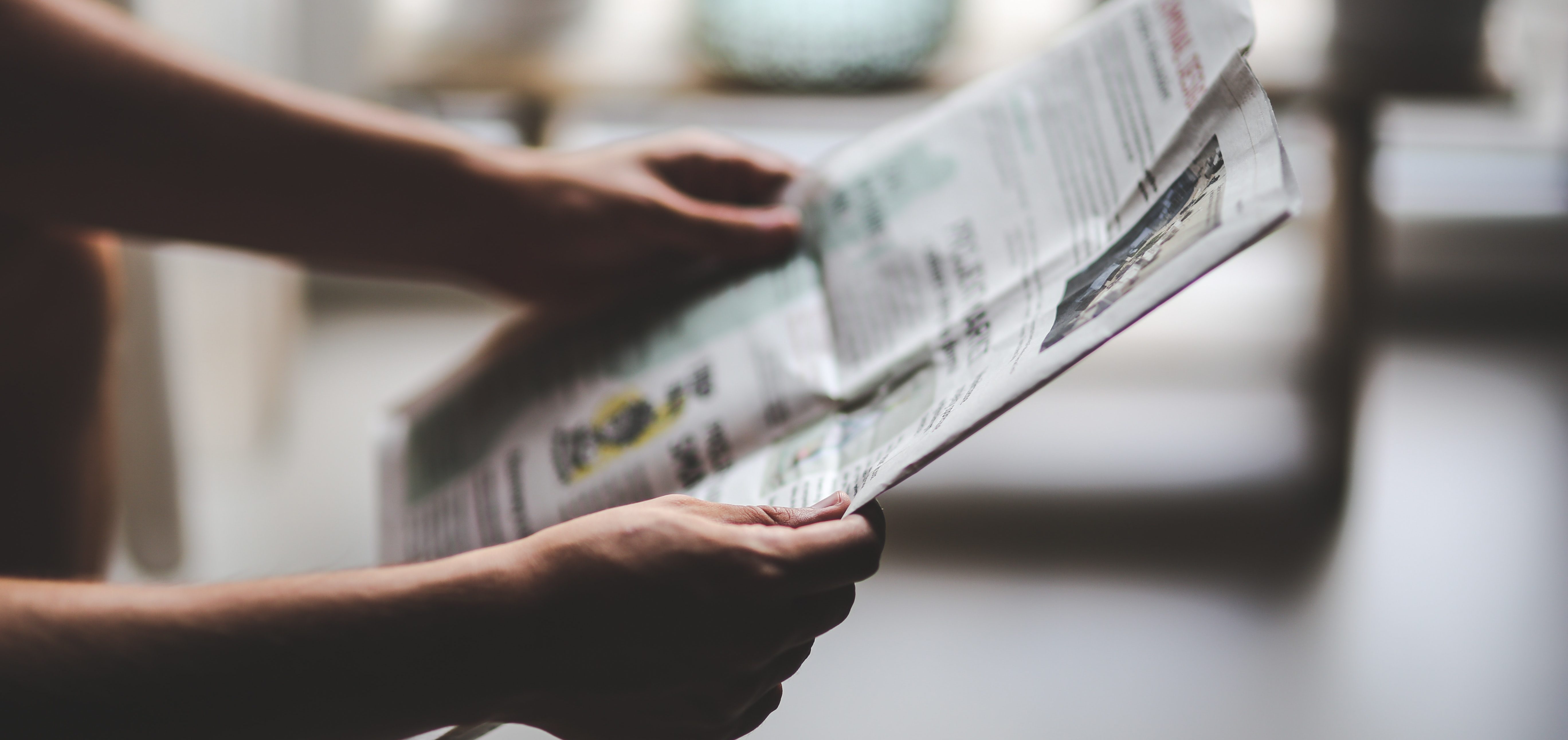 A closeup of a person's hands reading a newspaper.