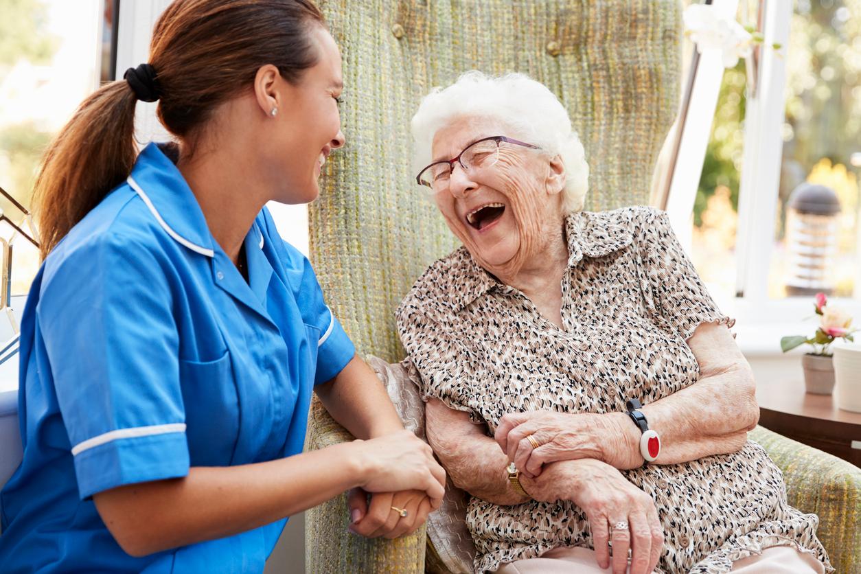 An elder woman laughs with her smiling personal supprt worker.