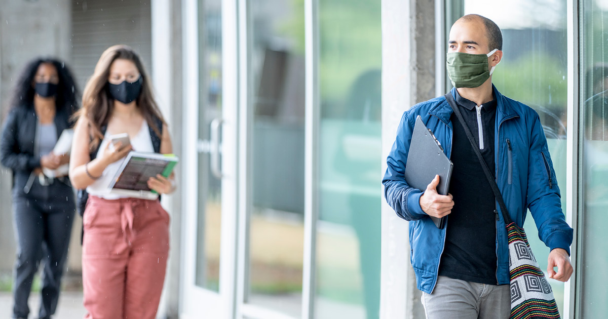 People wearing face masks walking outside a building. 