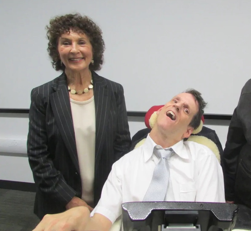 A photo of Melanie Panitch smiling beside Justin Clark in a tie. 