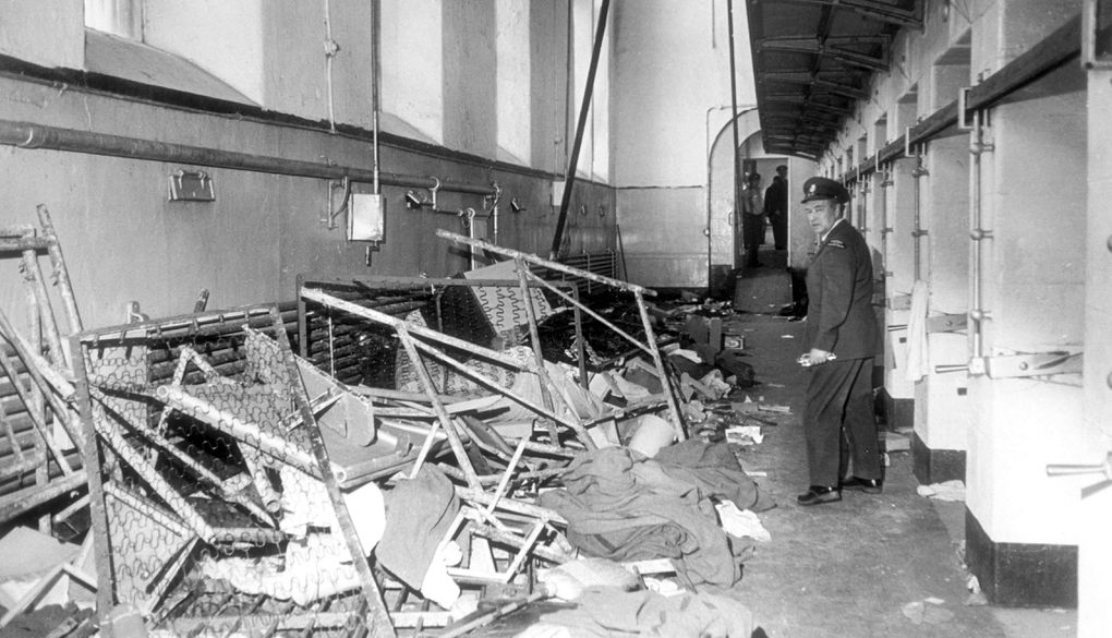A guard looks a destrcuted fence with debris inside the Kingston Penitentiary.