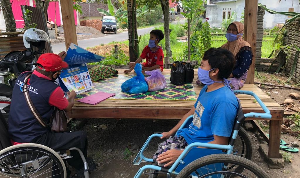 A group of Indonesian people with disabilties at an outdoor table with face masks.