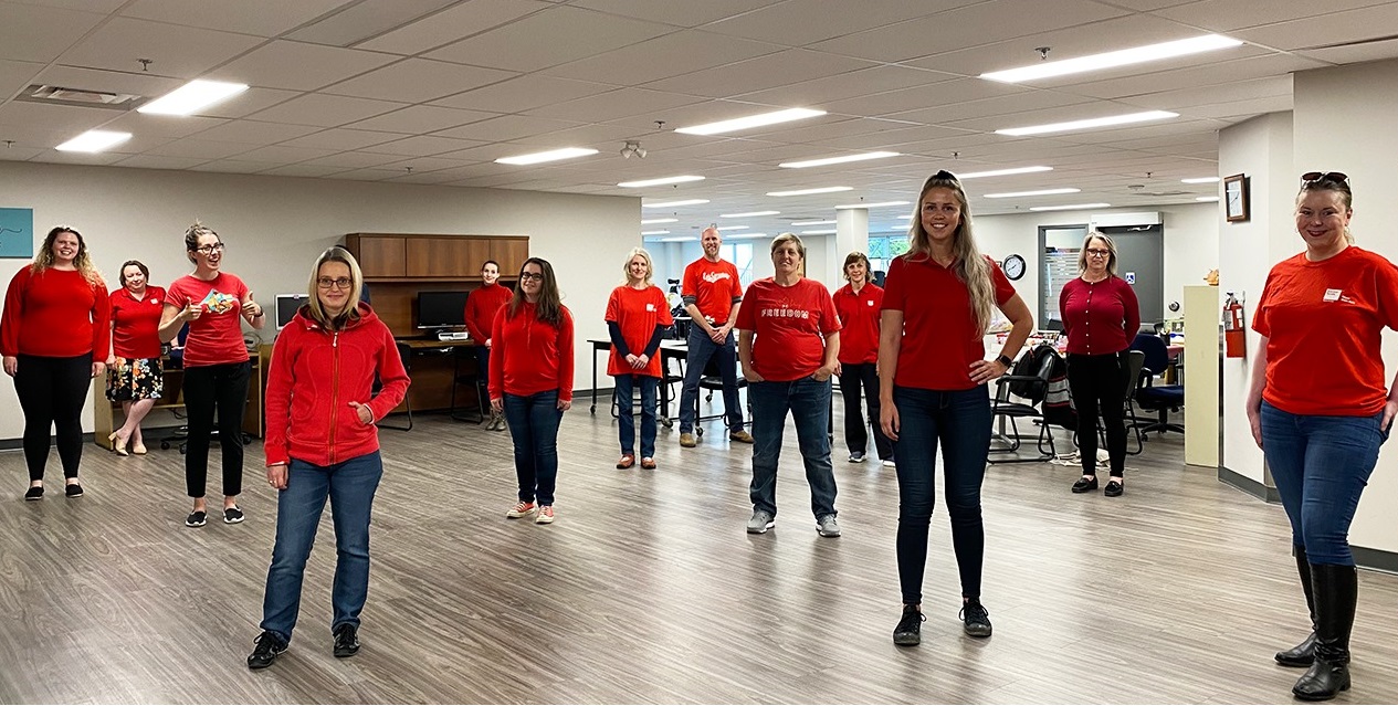 A photo from last year's Red Shirt Day of Easter Seals staff wearing red shirts and standing all spread out amongst each other in a large room. 