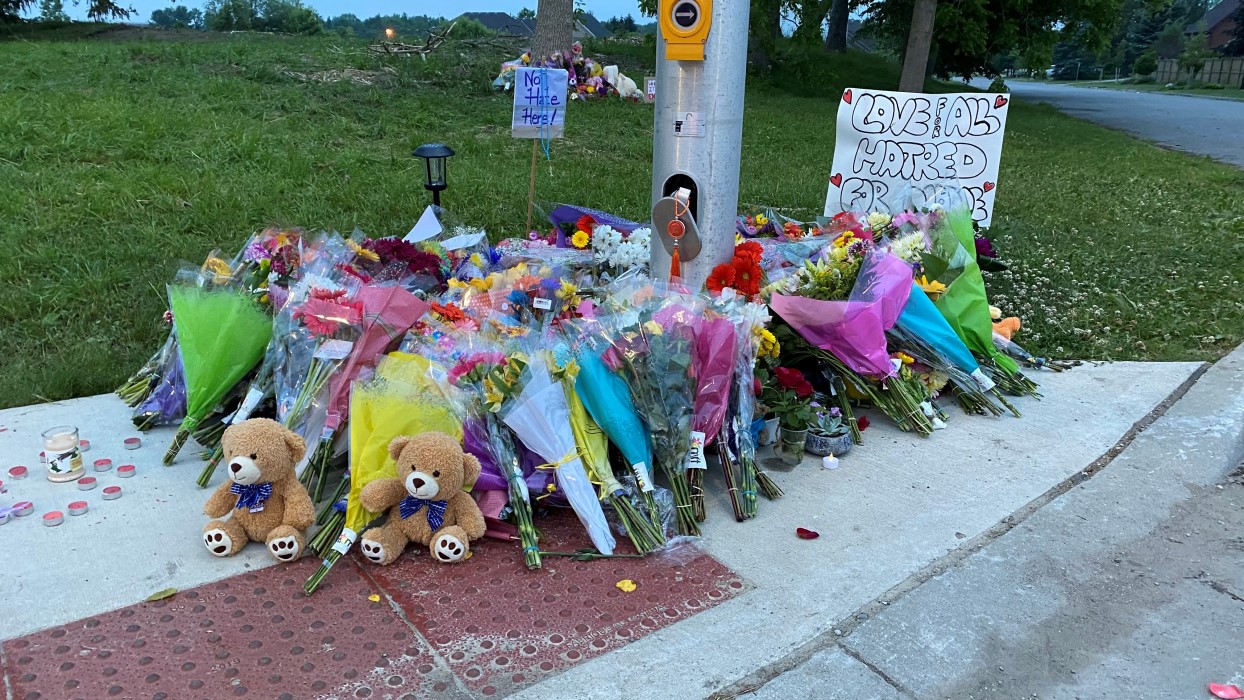 The sidewalk of the London truck attack covered with flowers, some candles, a couple of teddy bears and signs that read "no hate here" and "love for all hatred for none."