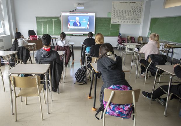 A photo of high school students wearing face masks and sitting at their school desks.