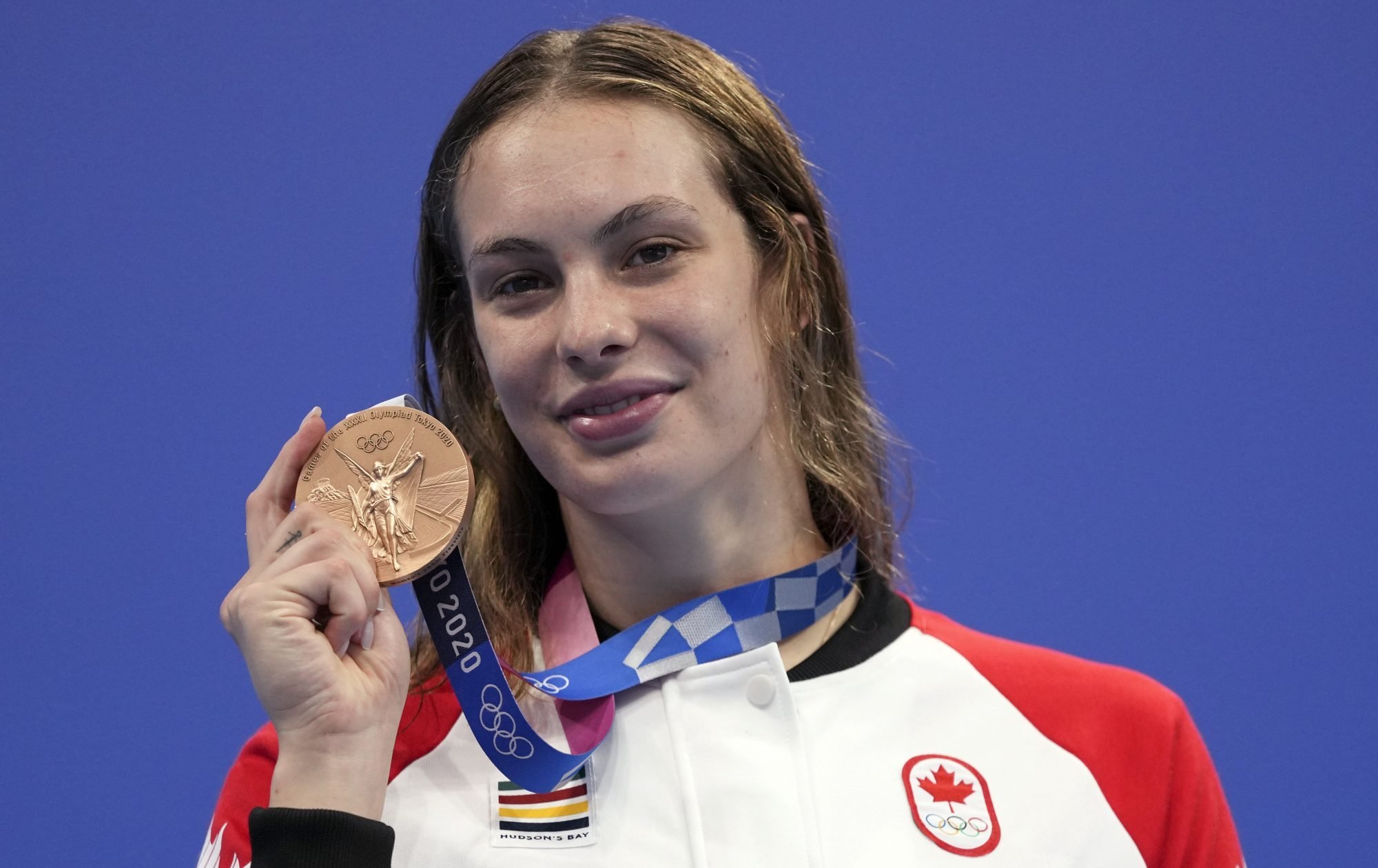 Penny Oleksiak holding her bronze medal at Tokyo Olympics