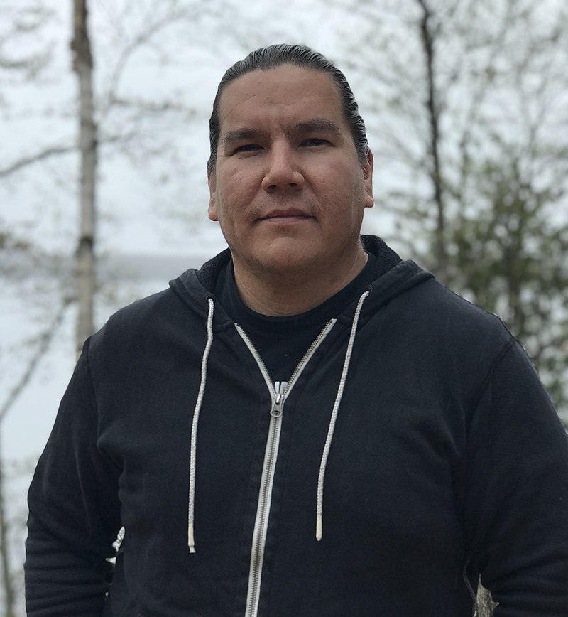 A photo of Waubgeshig Rice wearing a zipper hoodie outdoors in the winter. 