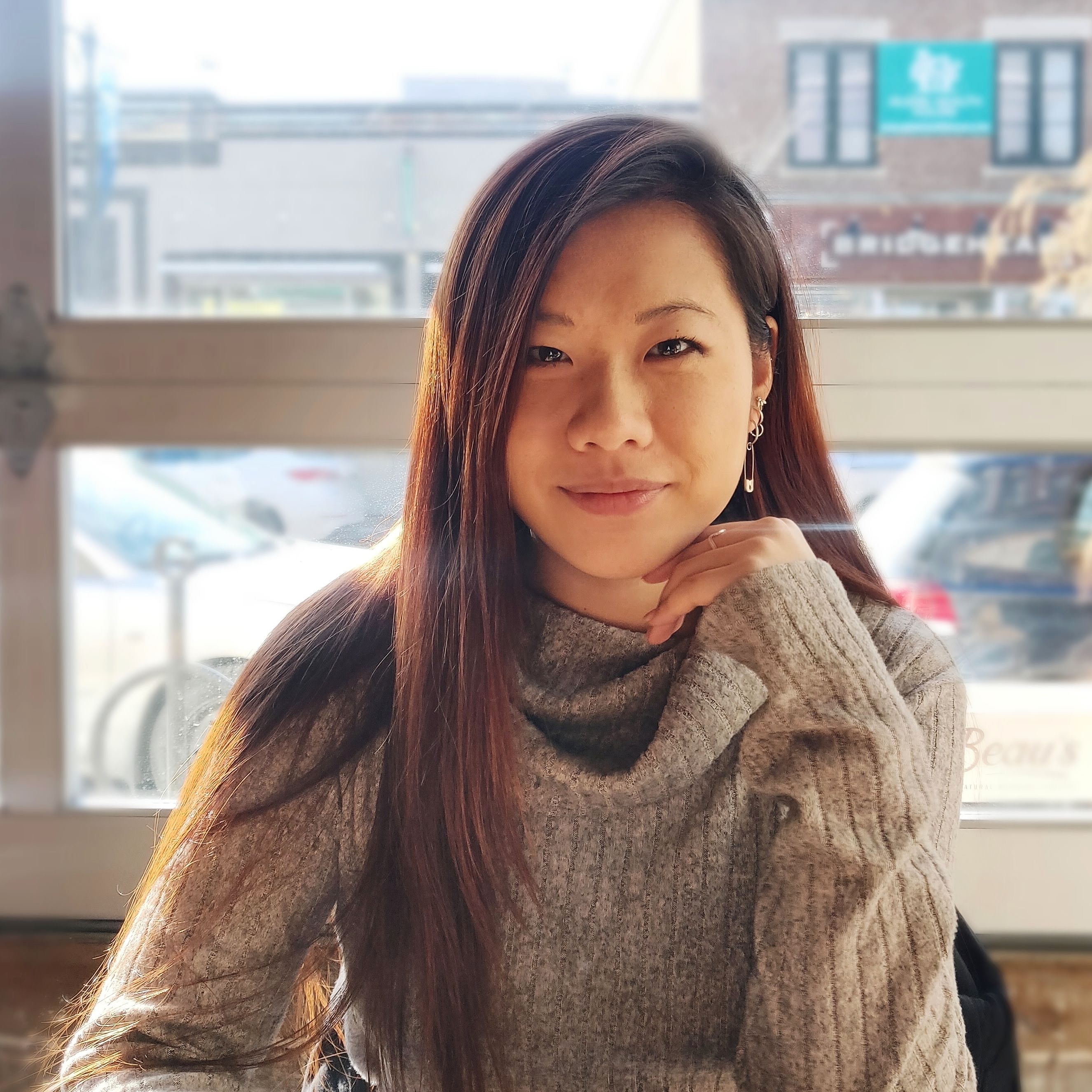 A photo of Jennifer Lim-Tamkican smiling with her hand under her chin. 