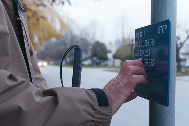 Person reading braille sign at bus stop