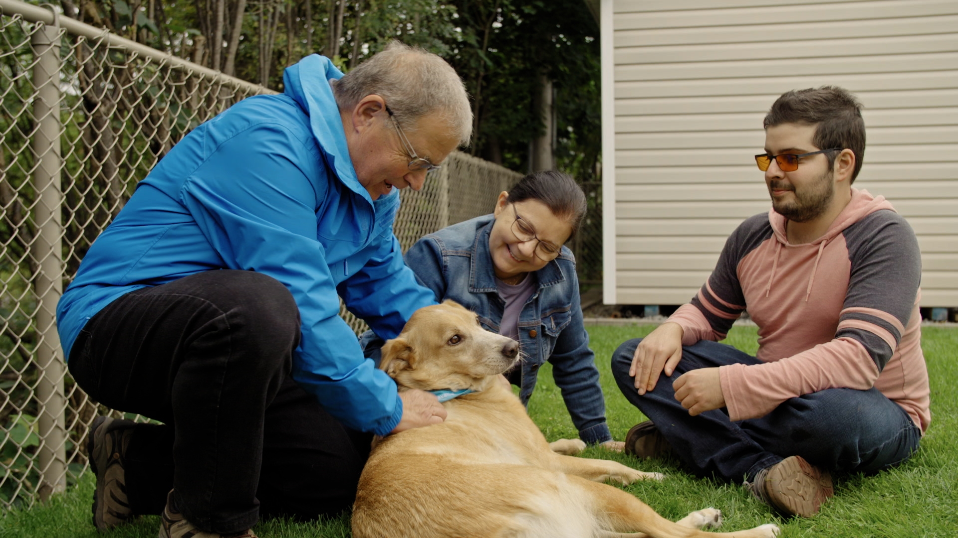 Trois personnes caressant un chien