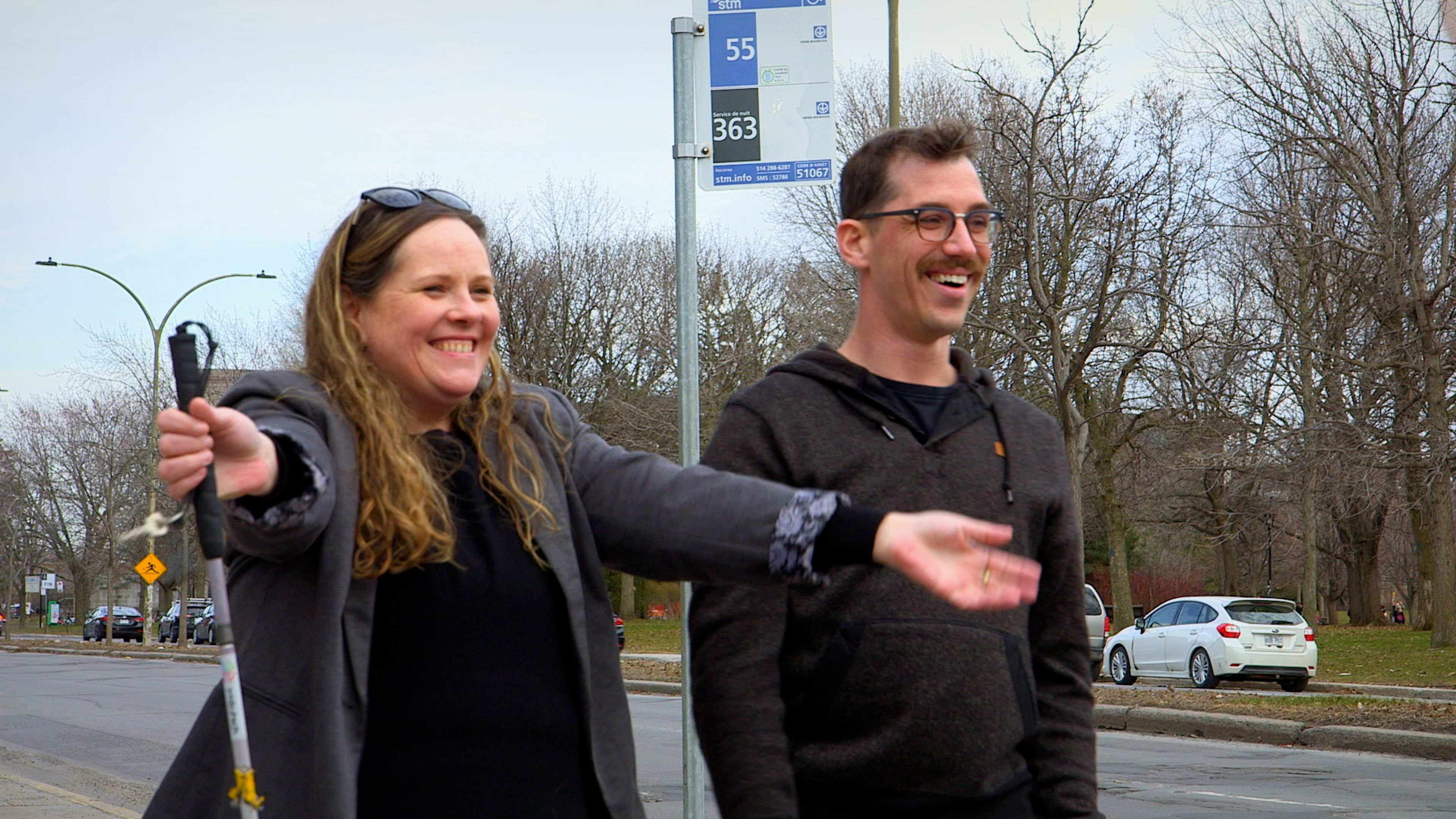 Christine tenant sa canne blanche, accompagnée d'un homme