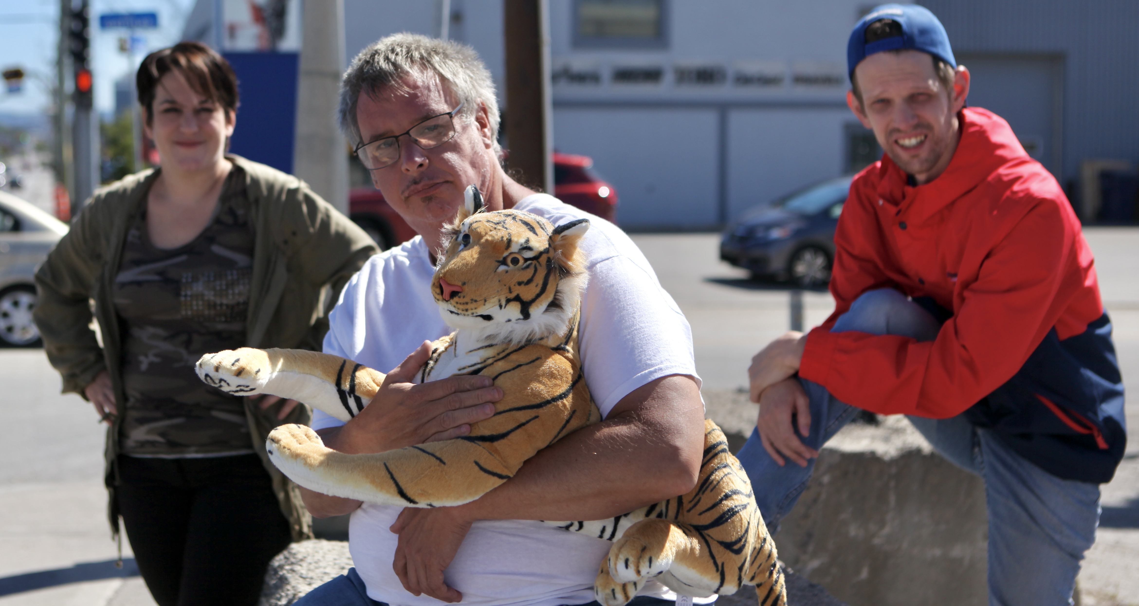 Louis, tenant un tigre en peluche dans ses mains, avec des amis, dans la rue.