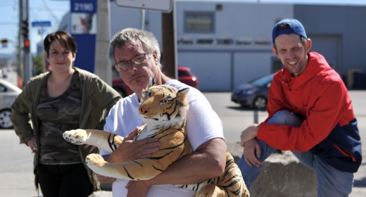 Louis, tenant un tigre en peluche dans ses mains, avec des amis, dans la rue.